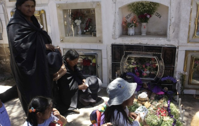 familiares de un difunto dando ofrendas en el día de Todos los Santos/ Foto archivo.