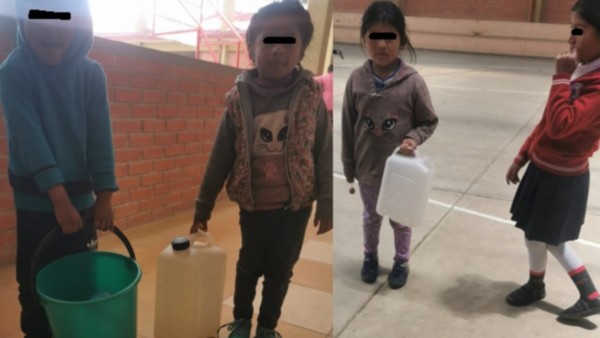 Niños van a su escuela con bidones de agua para usar el baño. Foto: Cortesía