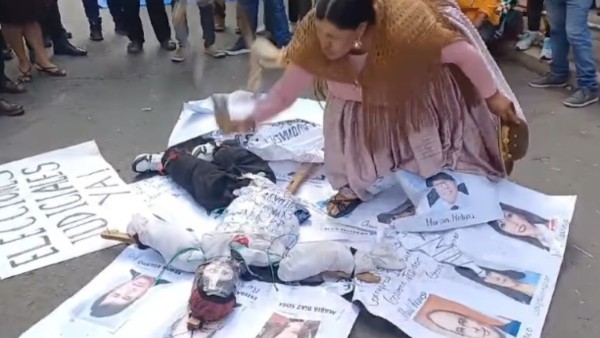 Una mujer chicotea a un muñeco. Foto: captura video