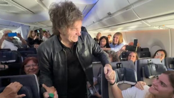 El presidente de Argentina, Javier Milei, saluda a personas en un vuelo comercial.