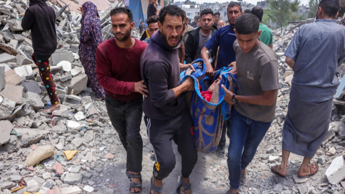 Palestinos llevan en una manta el cadáver de un hombre muerto en un ataque israelí. Foto: RFI