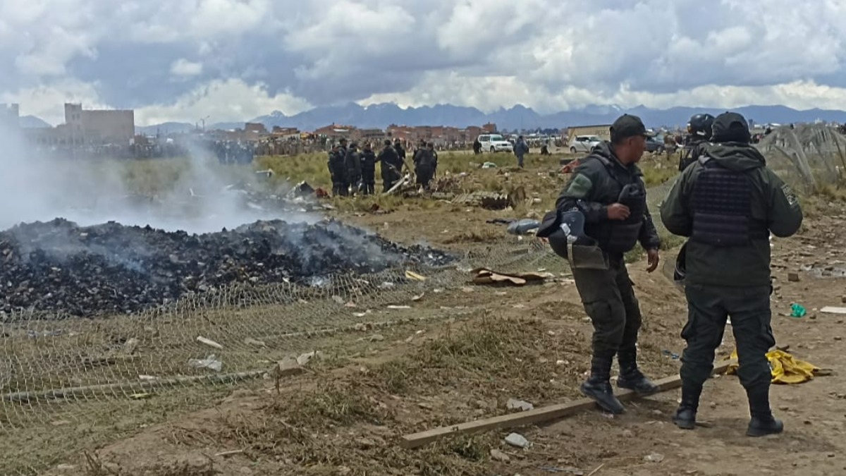 Policías resguardando el dinero que desparramó el avión accidentado. Foto: ANF